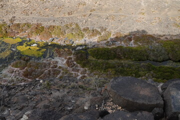 volcanic arid landscapes with trils, cliffs, and scattedred vegetation.
