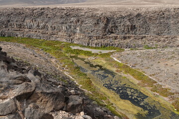 volcanic arid landscapes with trils, cliffs, and scattedred vegetation.
