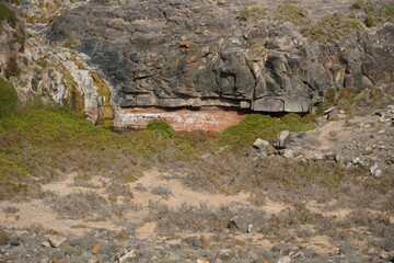 volcanic arid landscapes with trils, cliffs, and scattedred vegetation.