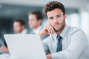 Confident businessman working on laptop in modern office.