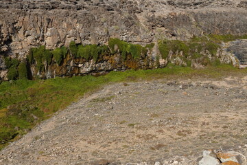 volcanic arid landscapes with trils, cliffs, and scattedred vegetation.