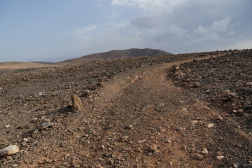 volcanic arid landscapes with trils, cliffs, and scattedred vegetation.