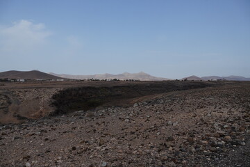 volcanic arid landscapes with trils, cliffs, and scattedred vegetation.