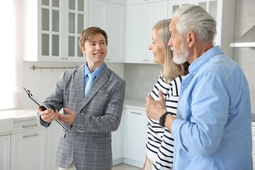 Smiling real estate agent working with couple in kitchen