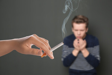 Passive smoking. Boy coughing because of woman smoking nearby on grey background. Selective focus