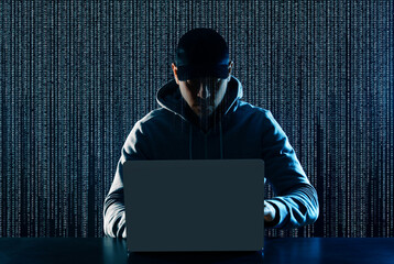 Cyber attack. Hacker working on laptop at table. Digital code behind him