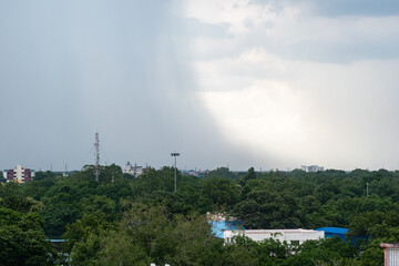 Dark clouds gather over Madurai as rain approaches the city and greenery thrives in the foreground