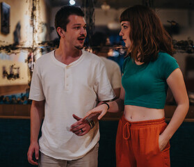 A young couple engages in a candid conversation indoors, showcasing connection, casual fashion, and...