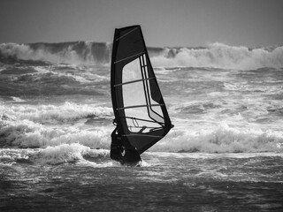 Water Sport Activity - Windsurfer Riding a Wave in Rough Sea on a Windy Day