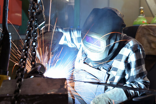Welder in protective clothing at the workplace in an industrial company in steel construction