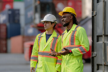 Industrial engineer standing at shipping container yard inspecting cargo delivering loading as plan. Cargo manager and diverse ethnic worker checking import export container at logistic terminal dock.