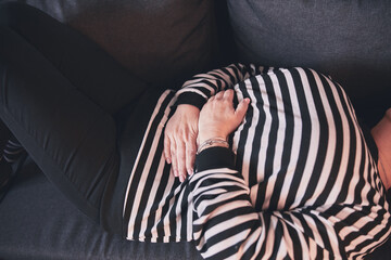 Woman with strong stomach ache, menstrual and digestive issues at home.