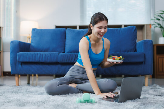 Young woman following online diet plan using laptop at home