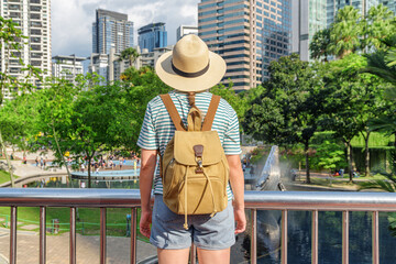 Female tourist in hat with backpack enjoying cityscape, Malaysia