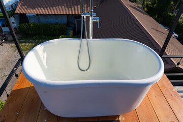 Phetchabun, Thailand - June, 06, 2025 :Outdoor freestanding bathtub surrounded by lush greenery and pebbles with mountain view in the background at Phetchabun, Thailand