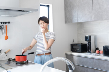 キッチンで料理をしながら困る女性