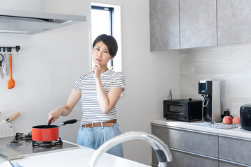 キッチンで料理をしながら困る女性