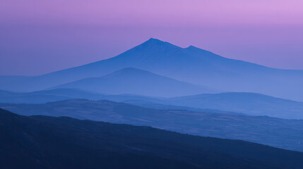 Obraz premium Mountain silhouette under twilight sky, serene blue tones blending into dusk, nature's quiet grandeur