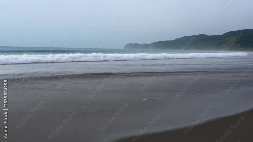 Poster waves crashing on a serene beach at dawn with lush cliffs in the background creating a peaceful coas