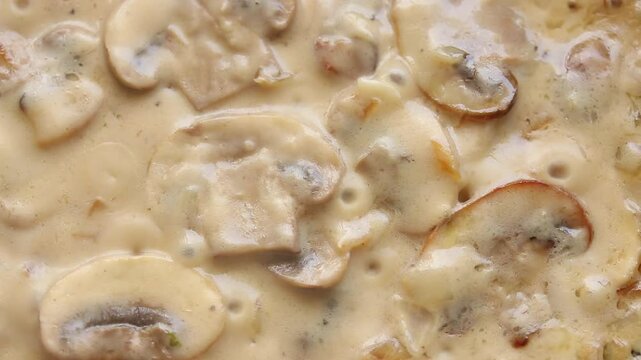 boiling creamy champignon mushroom sauce in pan. top view