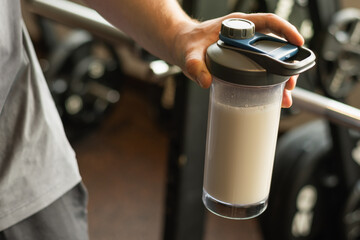 Close up of man hand with protein shaker at gym. Fitness healthy lifestyle concept. Supplement product, creatine, glutamine for workout.