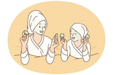 Two girls with hygienic mask on face rest lying on bed during rejuvenating spa treatment