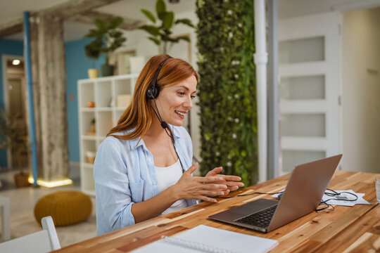 red head woman operator with headset talk on video call with client
