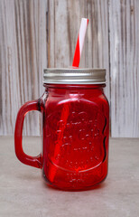 Red glass jar with a straw in it