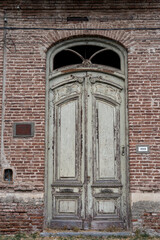 Old green wooden door with weathered texture and brick wall