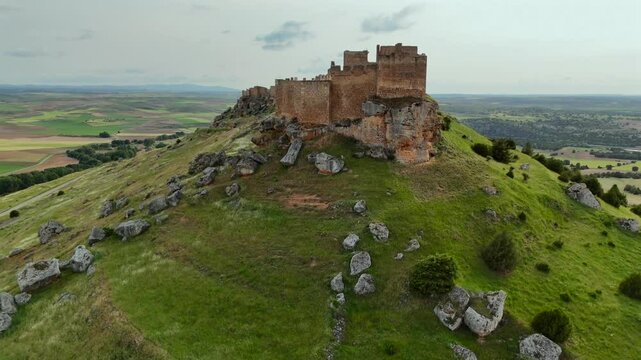 An aerial drone pull-back shot of the caliphate vast and imposing fortress of Gorm&aacute;z, in Soria, Spain. Shot taken at the golden minute.