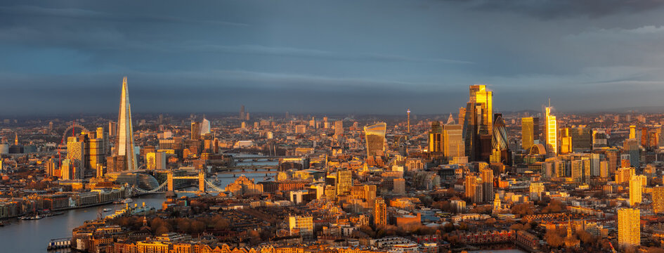 Panoramic, elevated view of the urban London skyline with soft, golden sunlight during sunrise, England, and cloudscape