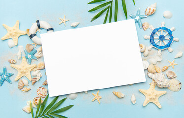 Blank card surrounded by seashells and starfish on sandy beach