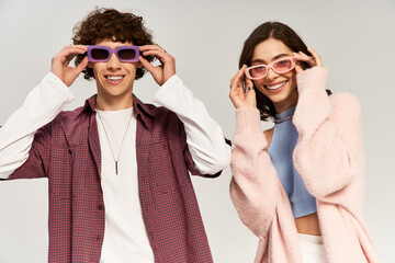 Stylish young couple playfully enjoying their time together in trendy purple sunglasses
