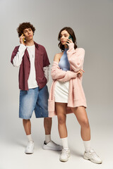 Fototapeta premium Young couple enjoying a stylish moment together while chatting on their phones