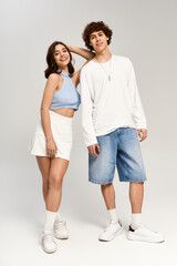Young couple sharing playful moments in stylish outfits against a neutral backdrop