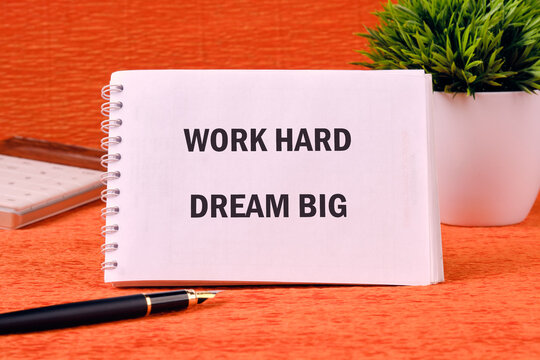 Motivational words WORK HARD DREAM BIG on a spiral notebook on an orange background