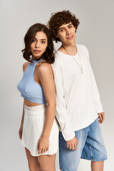 Young couple in stylish outfits sharing a joyful moment indoors in neutral tones and soft lighting