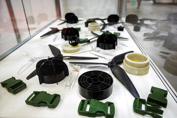 Assortment of plastic prototype parts displayed on a white surface, including drone propellers,...
