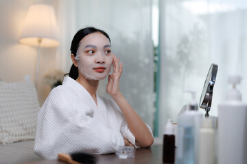 Young asian woman applying cosmetic face mask at home