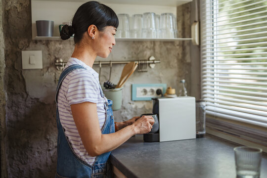 Japanese woman housewife use a capsule coffee machine prepare coffee