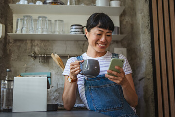 Japanese woman drink coffee and use mobile phone in a kitchen