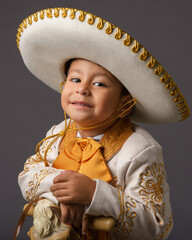 A boy, dressed in a traditional charro costume, with sombrero and ornamental details.