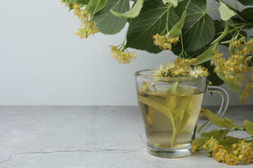 cup of herbal tea with linden flowers on wooden background