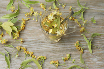 cup of herbal tea with linden flowers on wooden background