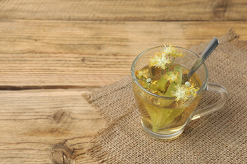 cup of herbal tea with linden flowers on wooden background