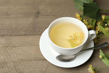 cup of herbal tea with linden flowers on wooden background