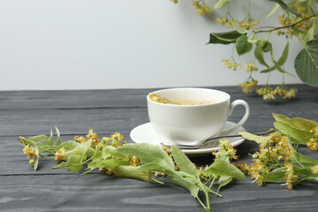 cup of herbal tea with linden flowers on wooden background