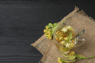 cup of herbal tea with linden flowers on wooden background