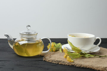 cup of herbal tea with linden flowers on wooden background