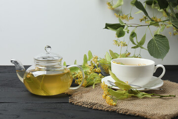 cup of herbal tea with linden flowers on wooden background